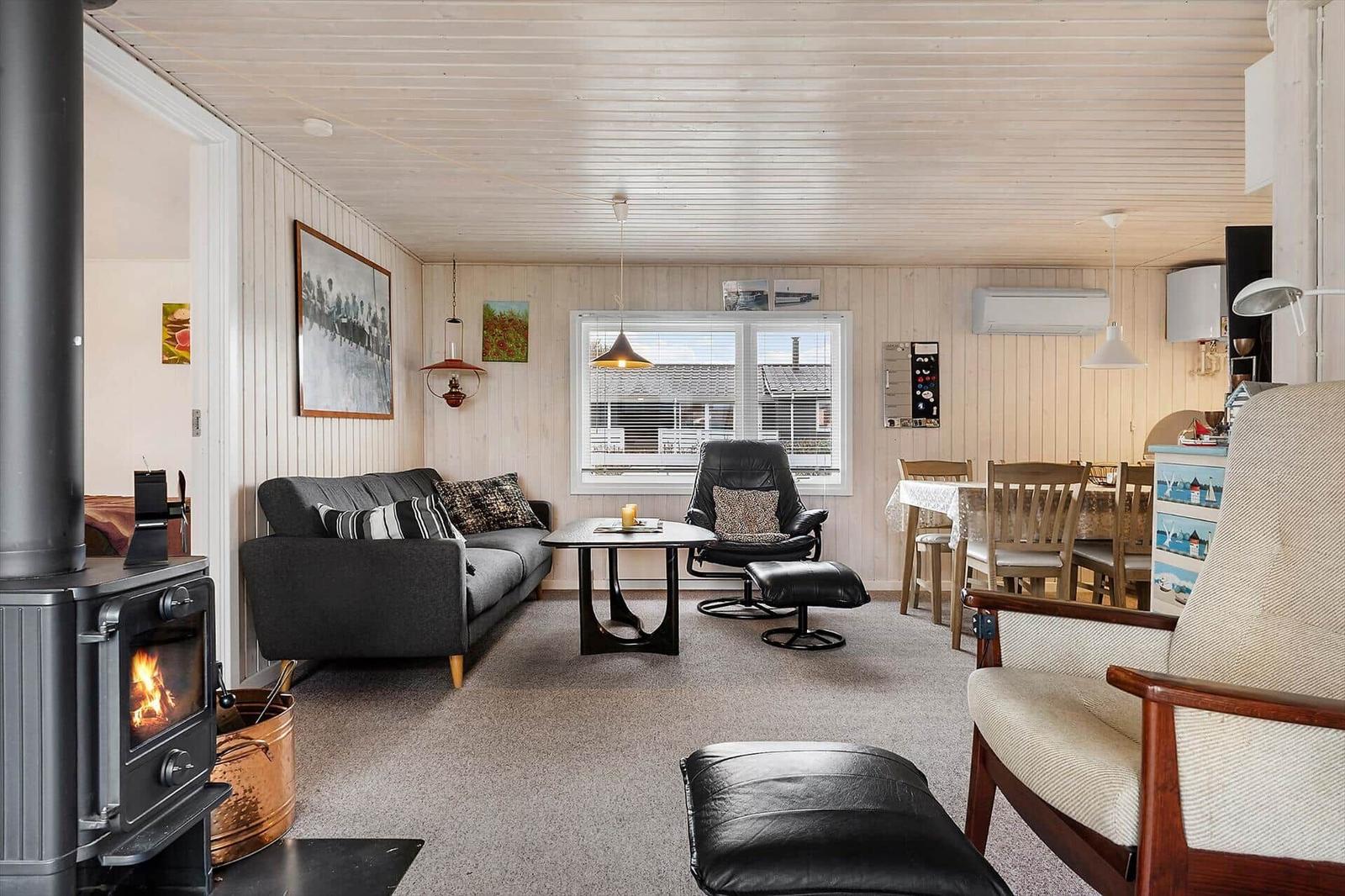 Wohnzimmer mit Sofa, Sessel und Kaminofen. Essbereich mit Tisch und Stühlen.