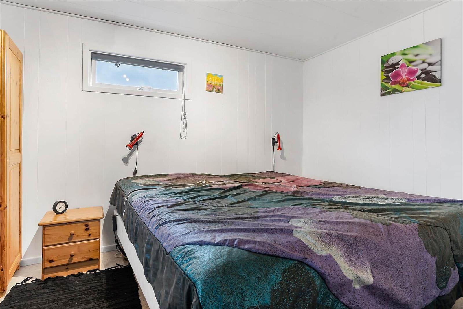 Schlafzimmer mit Bett, Nachttisch, Kleiderschrank und Wandbild.