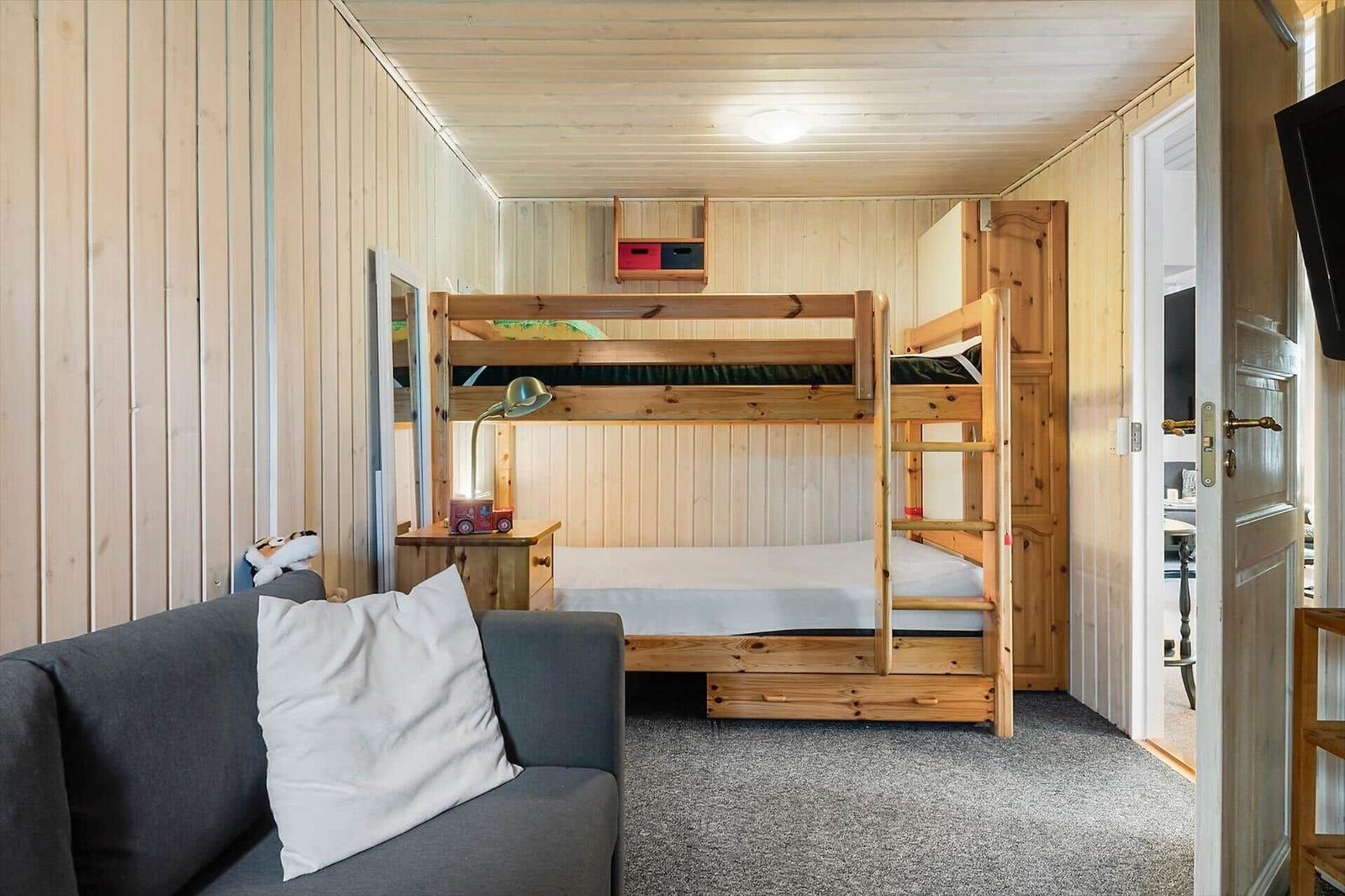 Zimmer mit Holzbett, Sofa und Tür zum Flur.