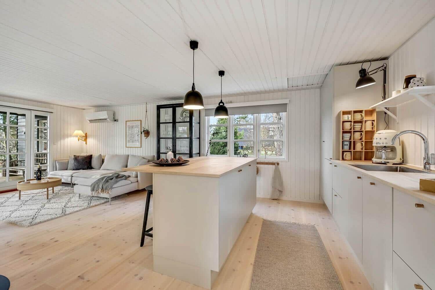 Küche mit Insel und Wohnbereich mit Sofa und Fenstern.