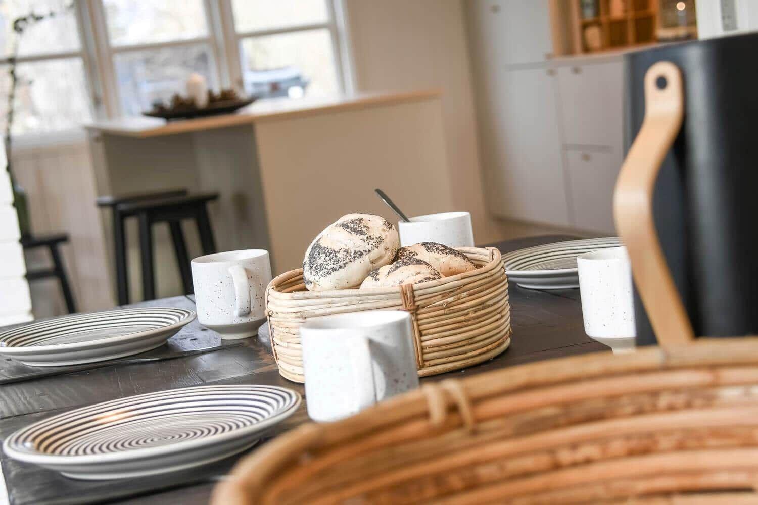 Tisch mit Tellern, Tassen und Brot im Essbereich.