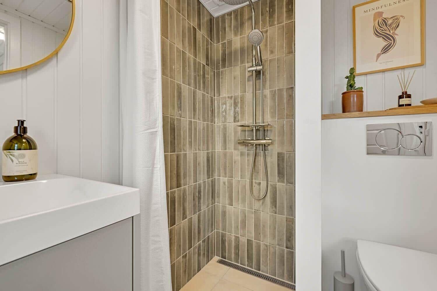 Dusche mit braunen Fliesen, Waschbecken und Toilette im Badezimmer.