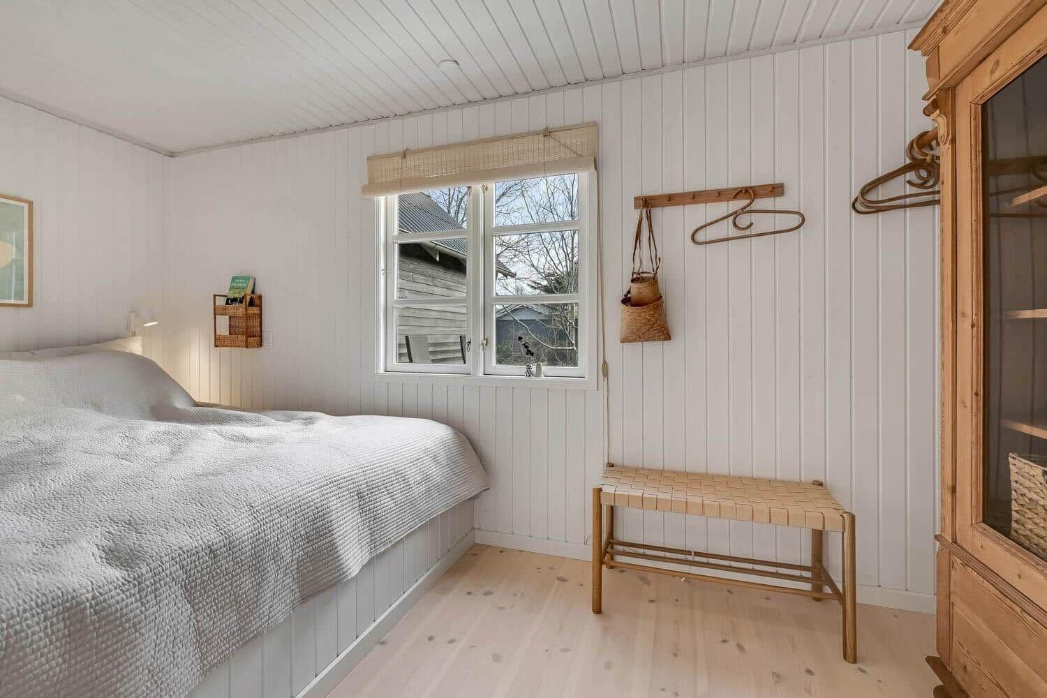 Schlafzimmer mit Bett, Fenster und Holzmöbeln.