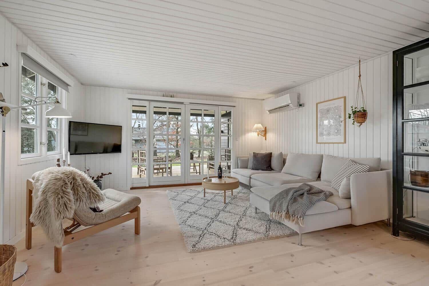 Wohnzimmer mit Sofa, Teppich und Fernseher an der Wand.