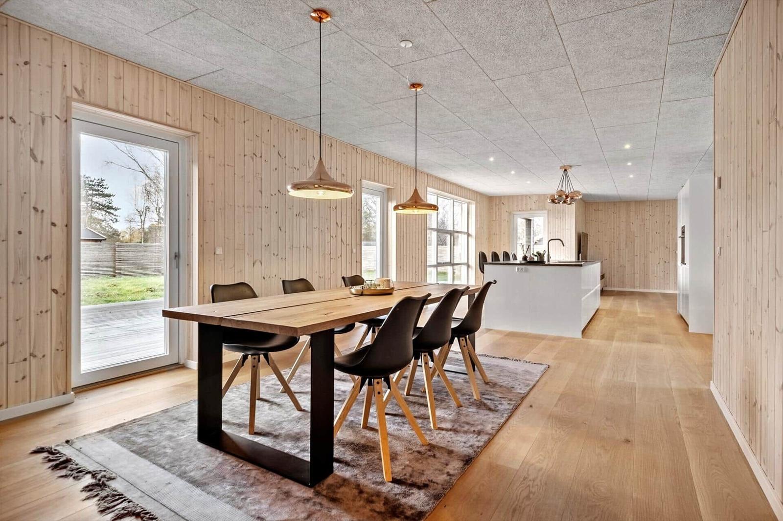 Essbereich mit Holztisch, Stühlen und Kücheninsel im Hintergrund.