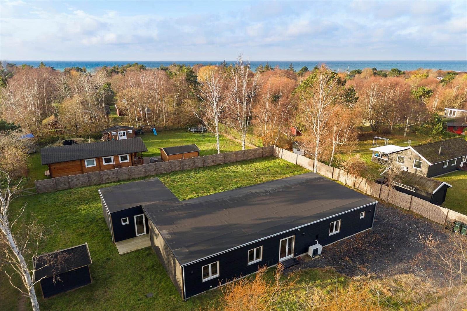 Moderne schwarze Ferienhaus mit Garten und Blick auf Meer.