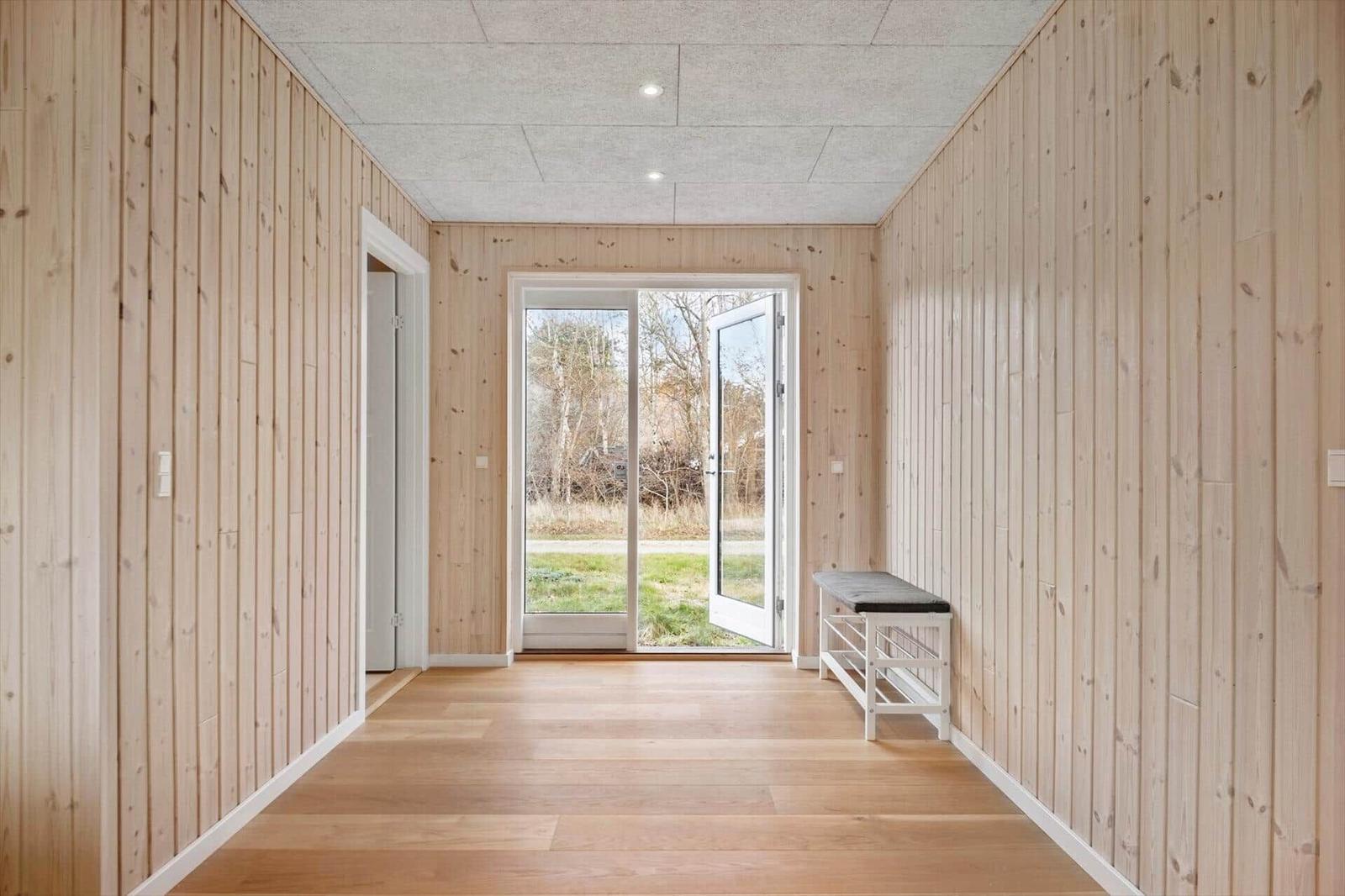 Hallenraum mit Holzwänden, Boden und Tür zur Außenterrasse.