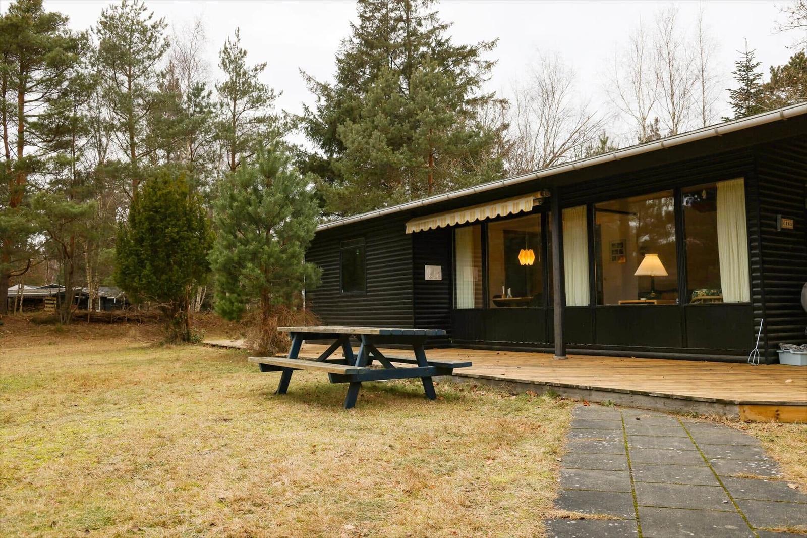 Wooden house with terrace and picnic table in the woods