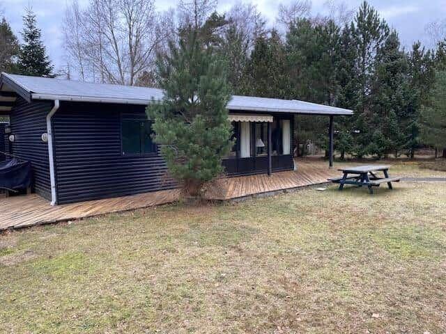 Wooden house with porch, picnic table, and tree in yard