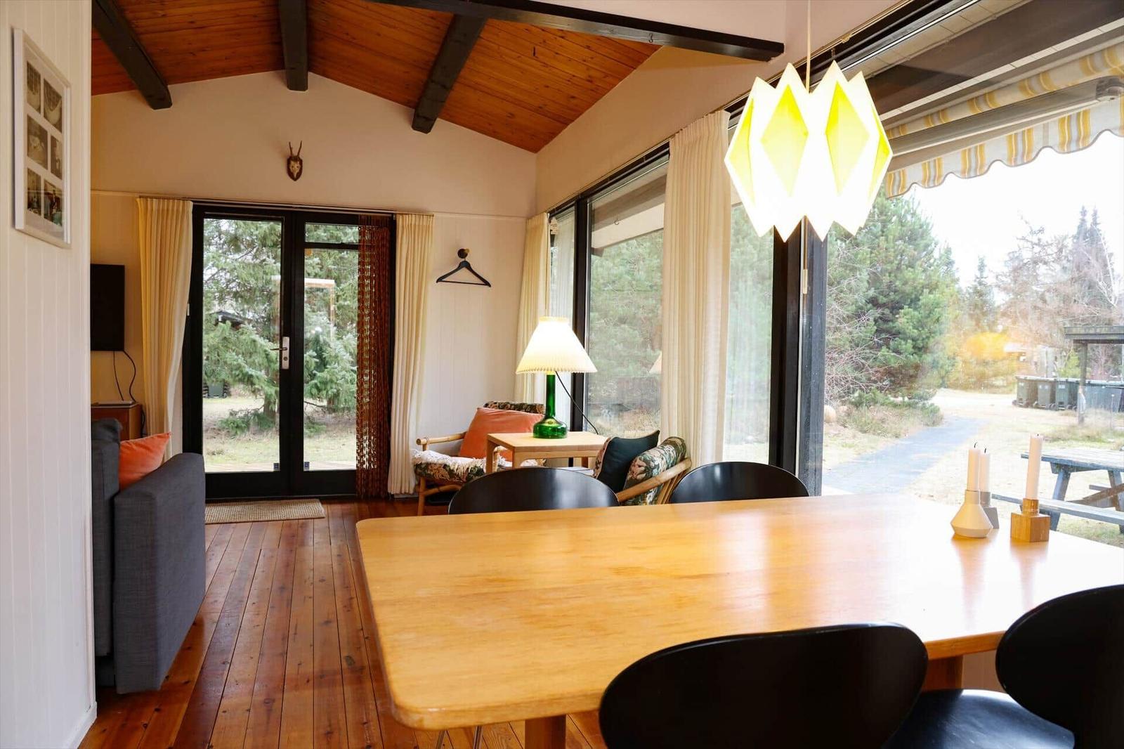 Dining room with wooden table, black chairs, and large window view of the forest.