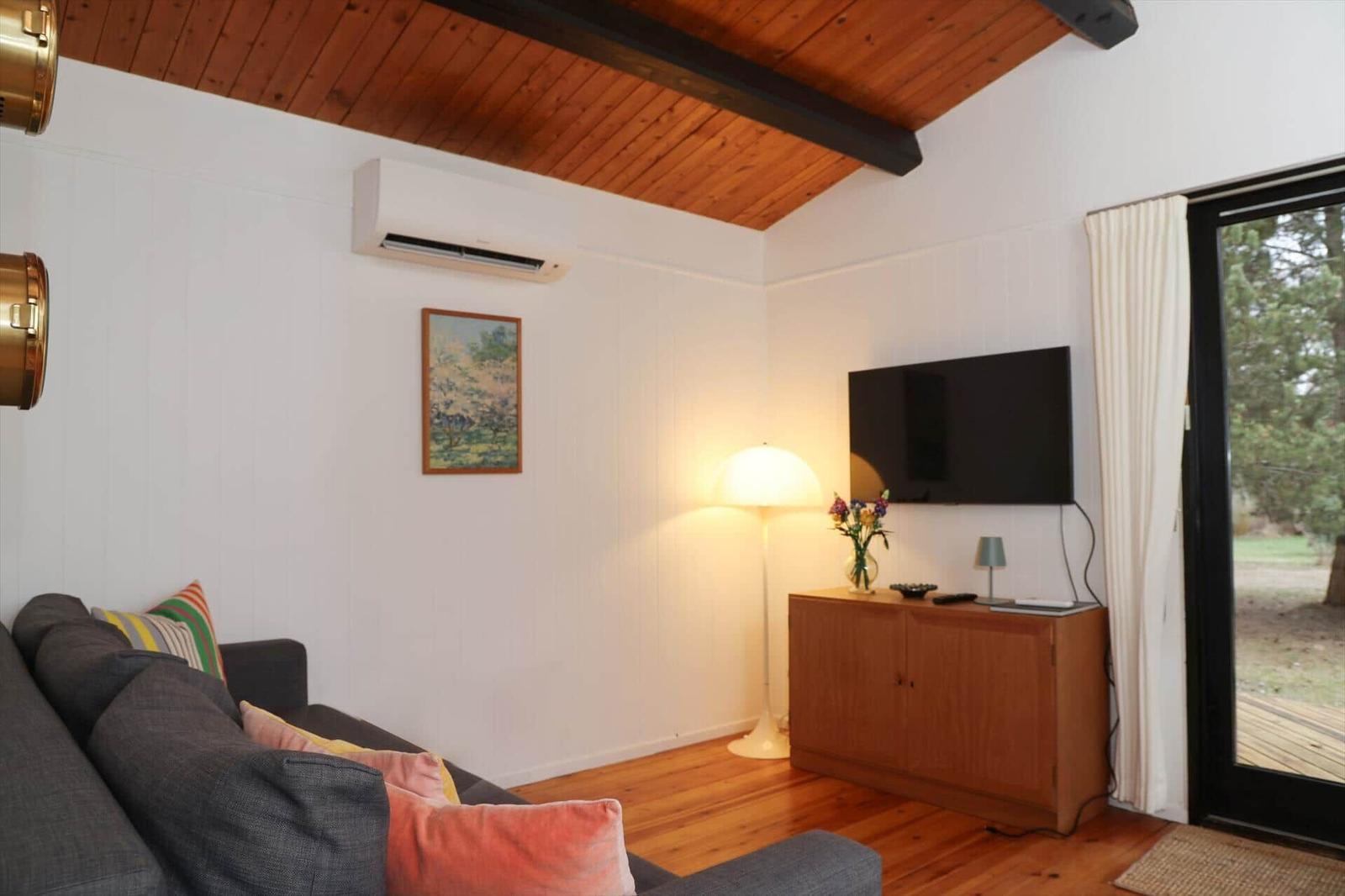 Living room with sofa, TV, and wooden floor. Door leads to terrace.