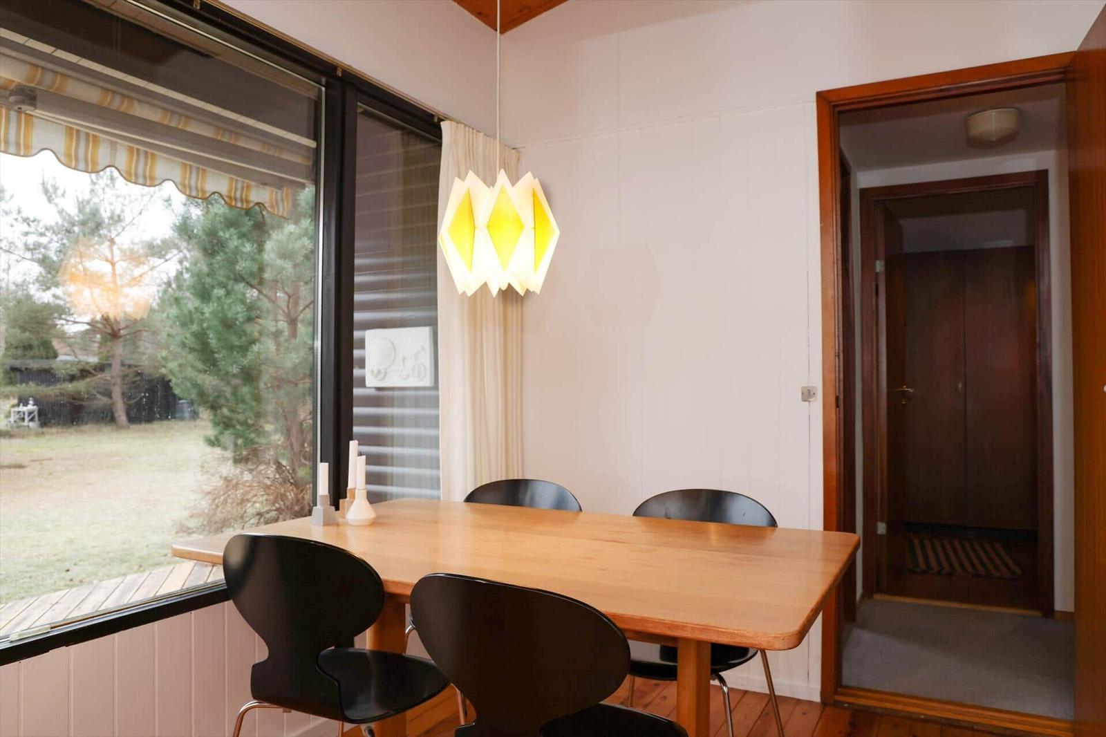 Dining room with wooden table, black chairs, and large window to the garden.