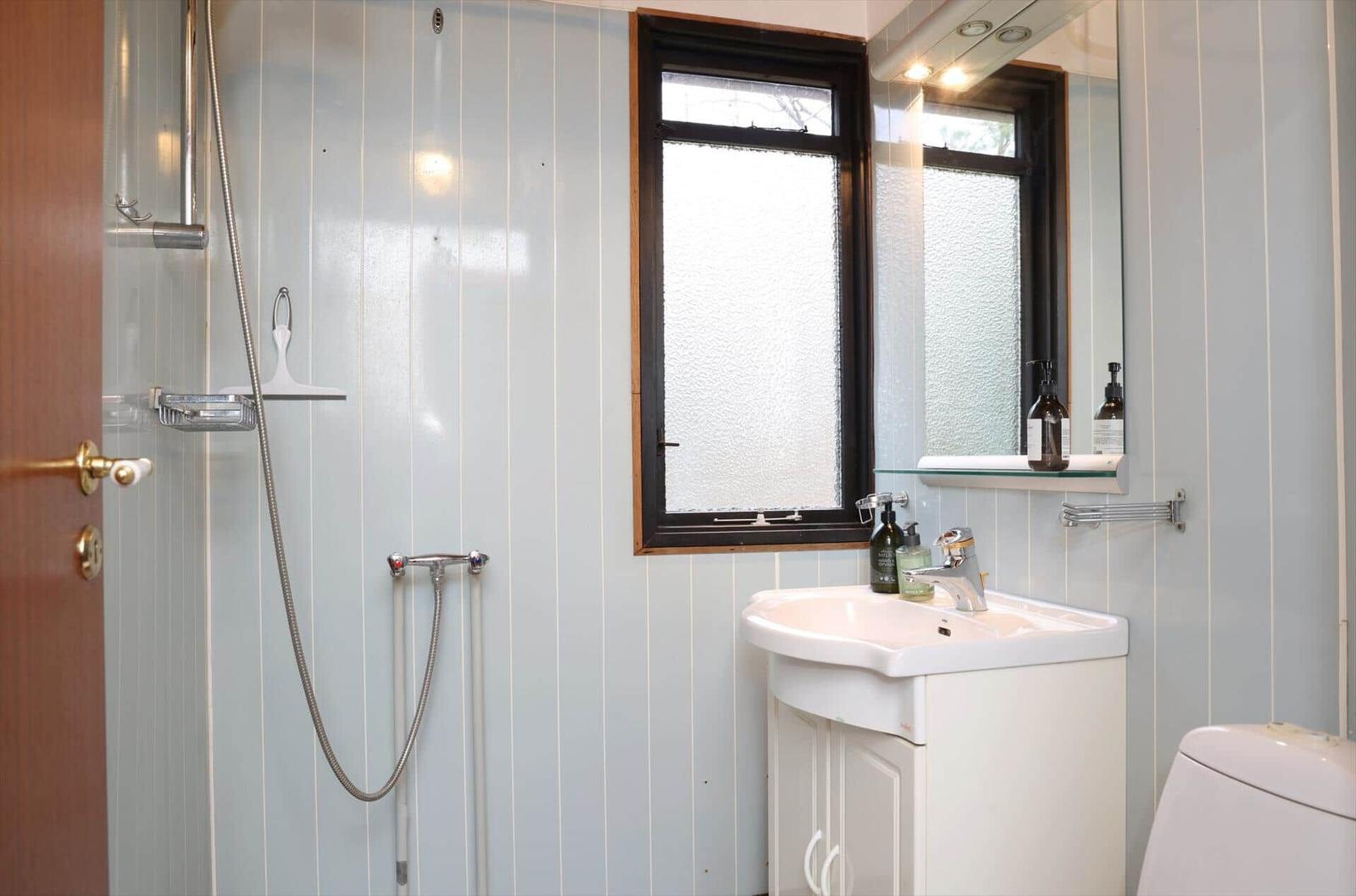Bathroom with shower, sink, and toilet. Window with frosted glass.