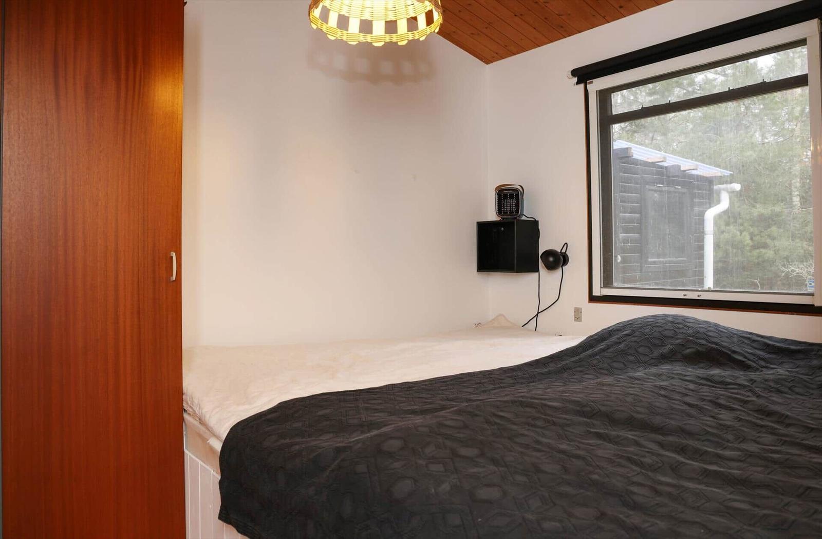 Bedroom with bed, window, and wooden ceiling.