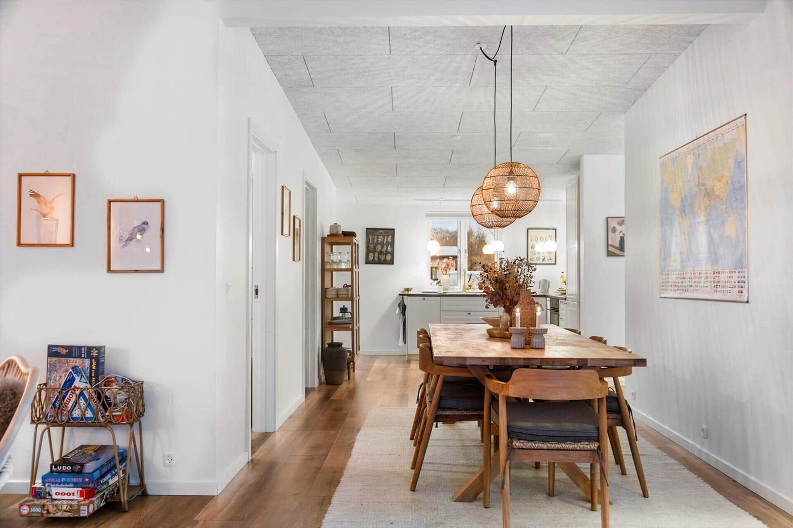 Dining area with wooden table, chairs, and world map. Kitchen in background.