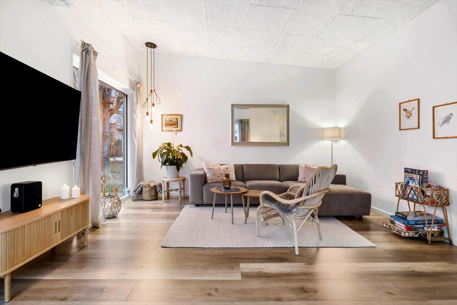 Living room with sofa, armchair, TV, and large windows.