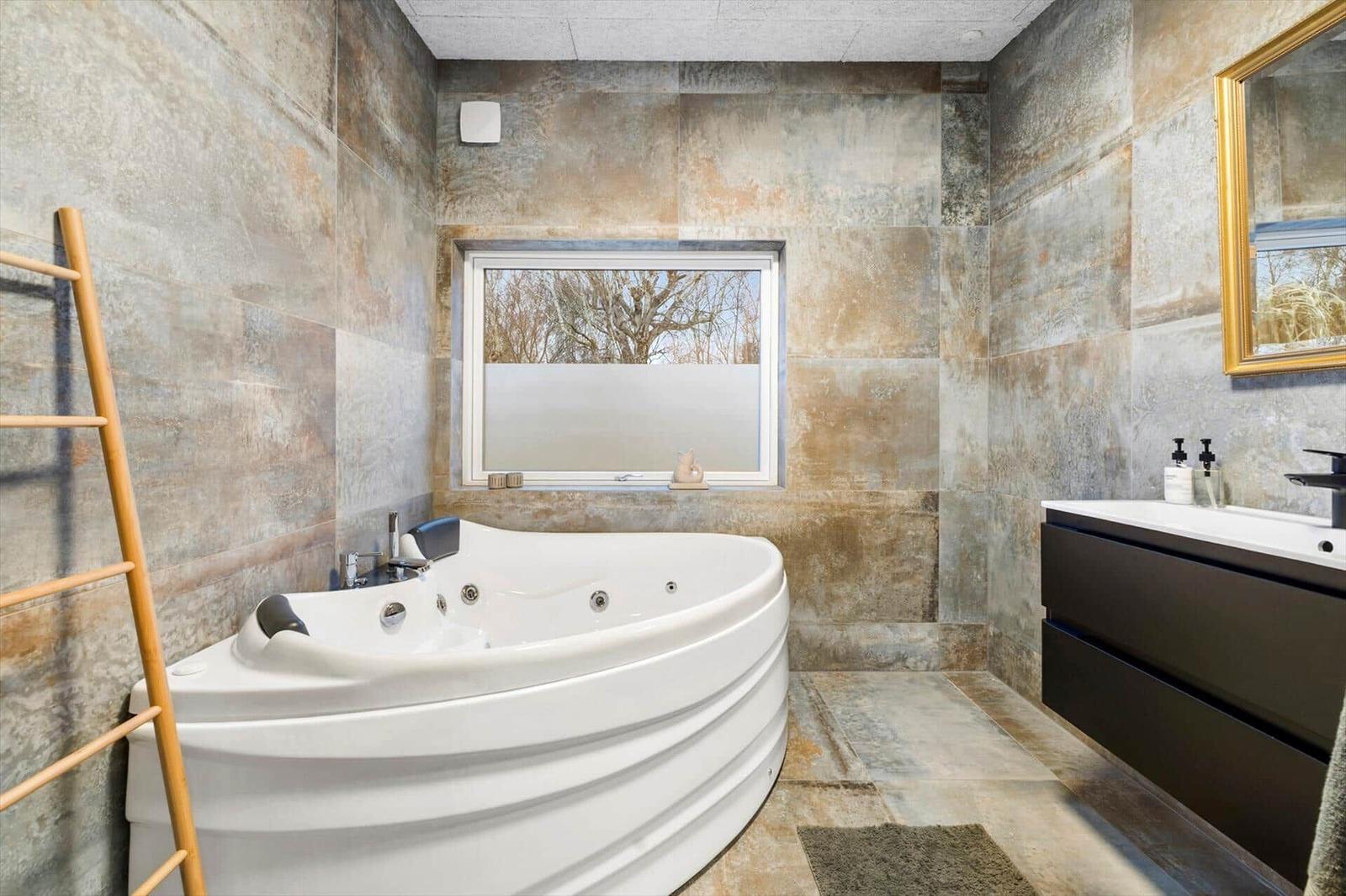 Bath with whirlpool, wall cladding, and sink with mirror.