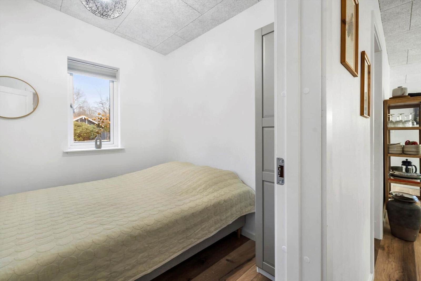 Bedroom with bed, window, and mirror on the wall.
