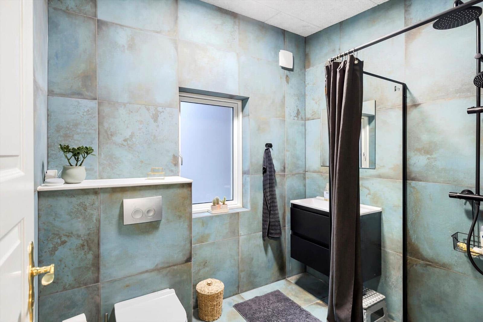 Bathroom with blue tiles, shower, sink, and toilet.