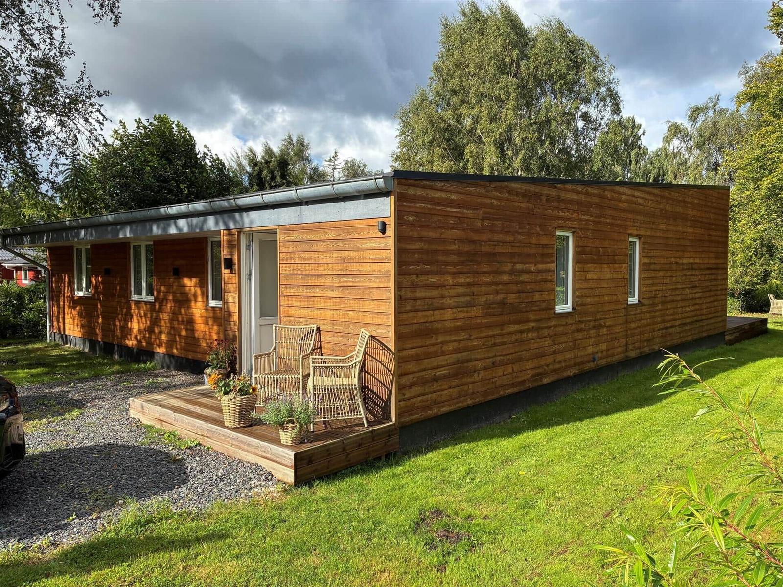 Wooden cabin with terrace and garden. Furniture and plants on the veranda.
