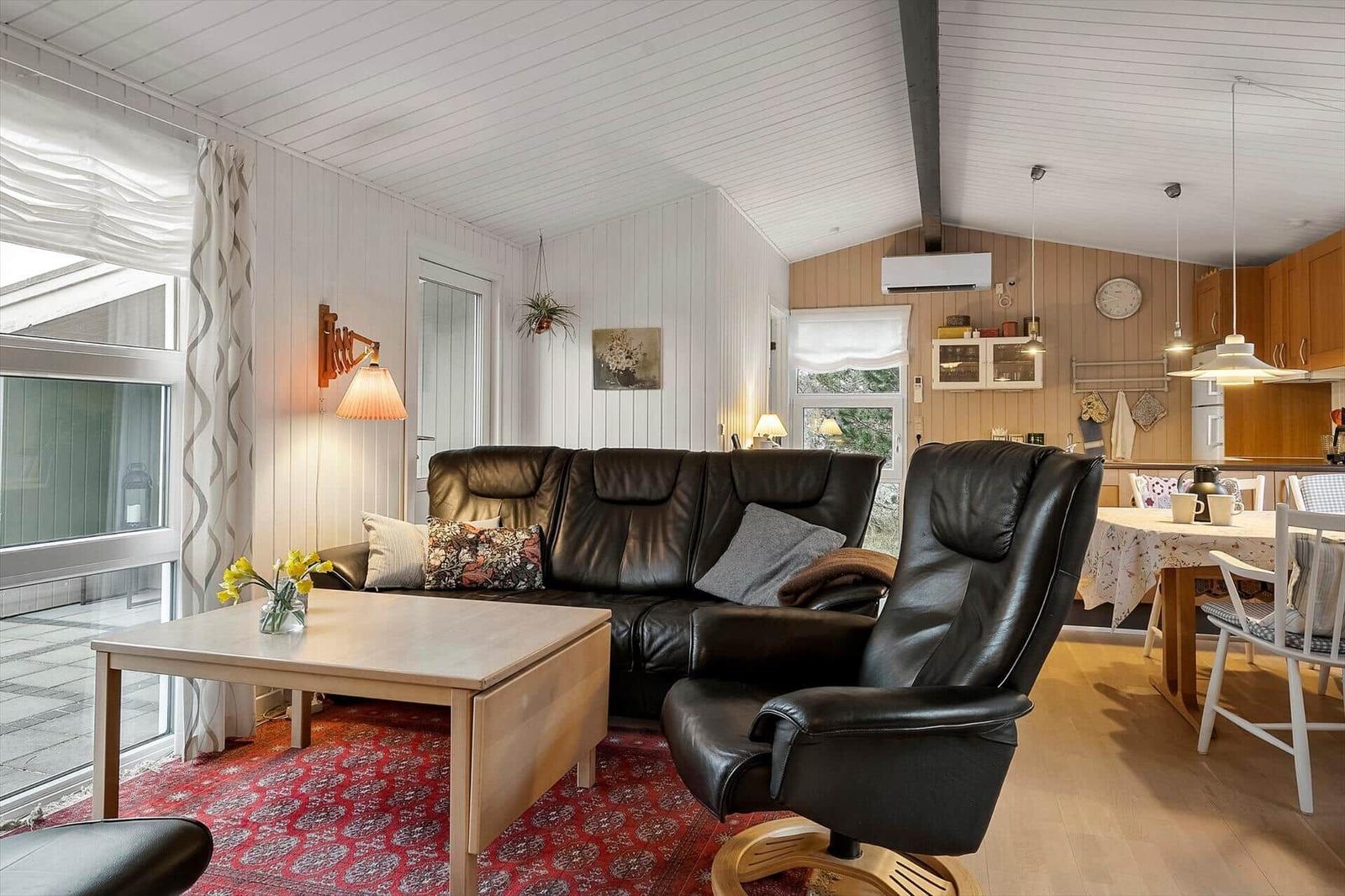 Wohnzimmer mit Ledersofa, Essbereich und Küche im Hintergrund.