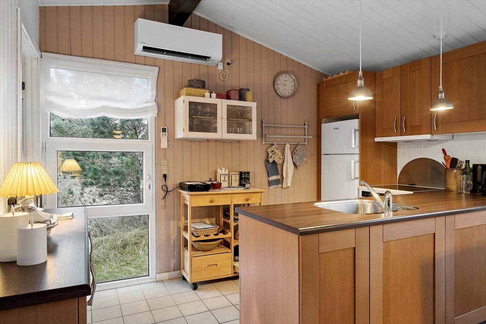 Küche mit Holzschränken, Kücheninsel und Fenster zum Garten.