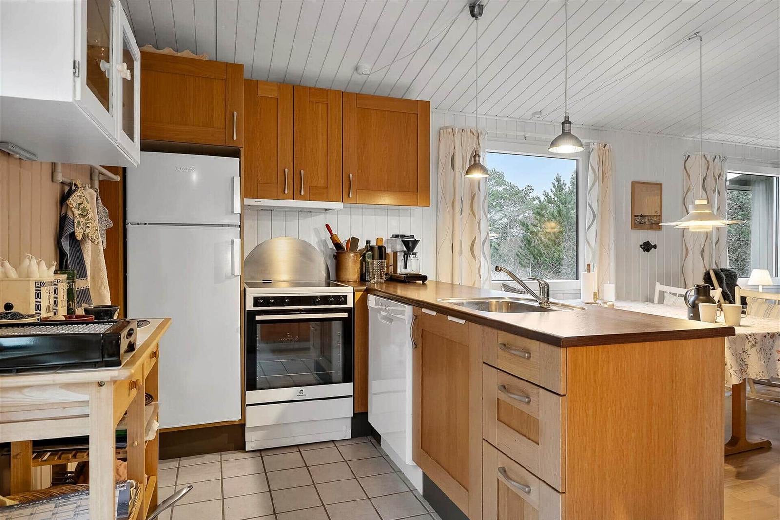 Küche mit Holzschränken, Kühlschrank und Fensterblick