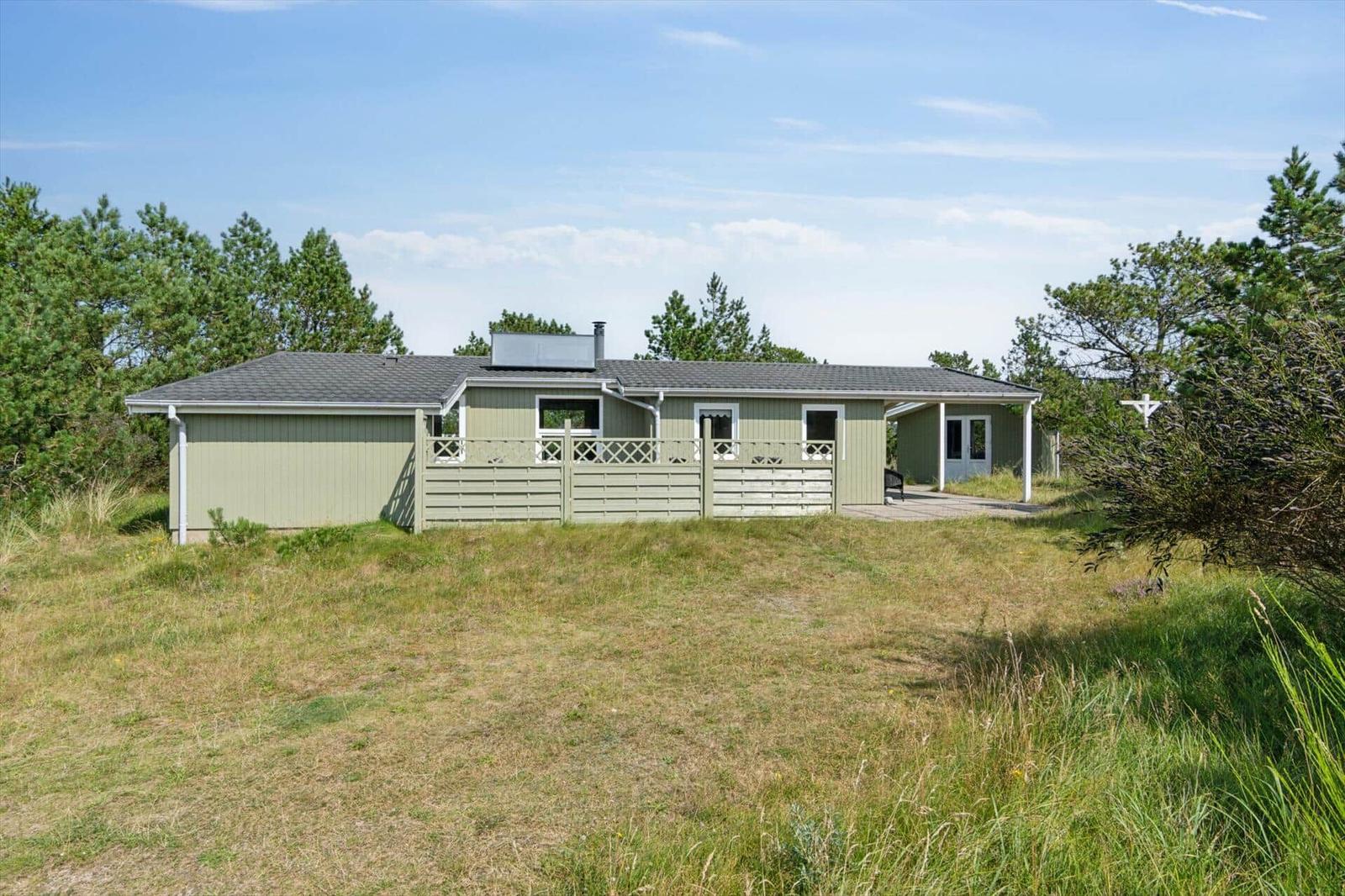 Ein Haus mit grünem Holzverkleidung und weißen Fenstern, umgeben von Gras und Bäumen.