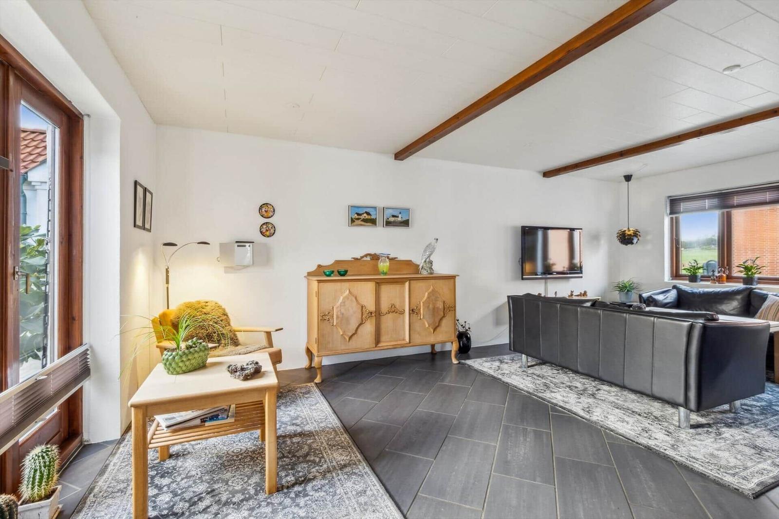 Living room with sofa, sideboard, and TV mounted on the wall.