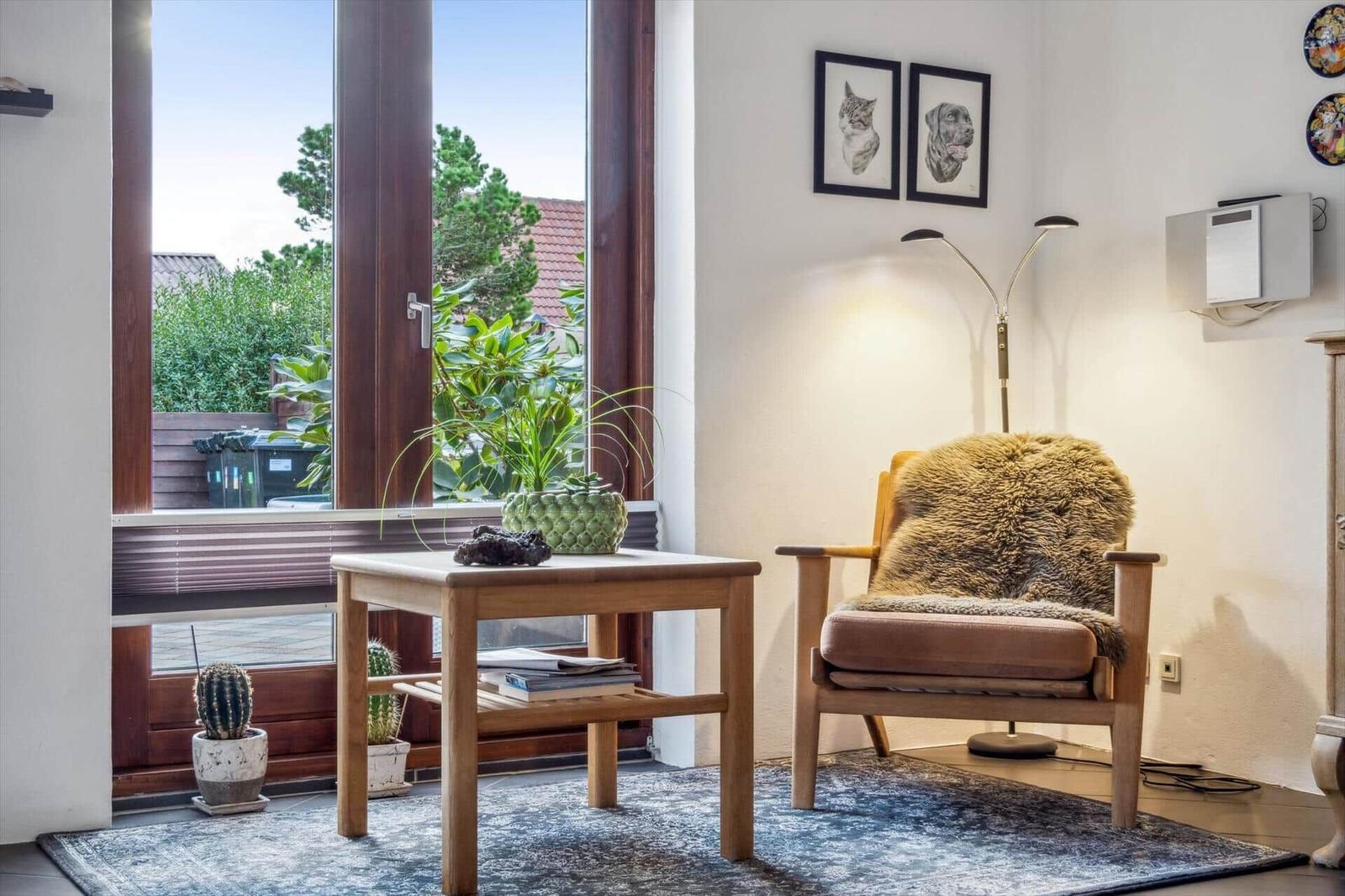 A room with a chair, table, and window to the outdoor terrace.