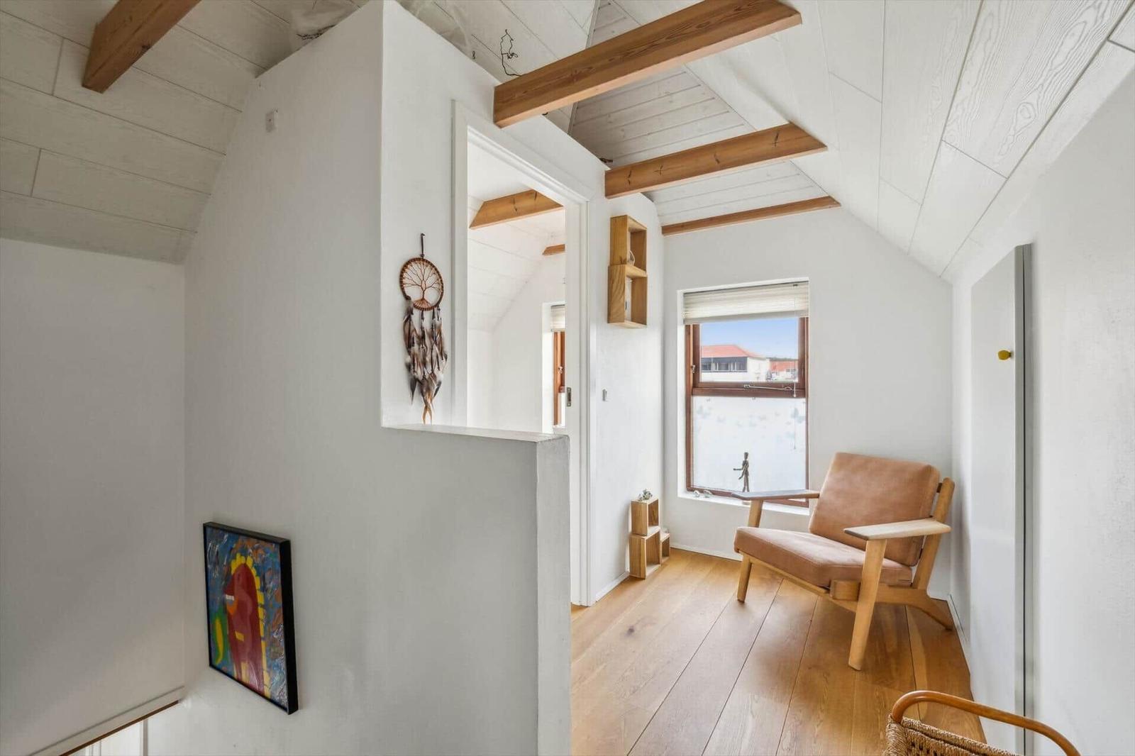 Room with wooden beams, window, chair, and wall decor.