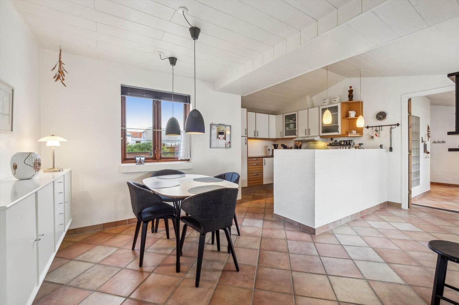 Dining area with table and chairs, kitchen with counter and window.