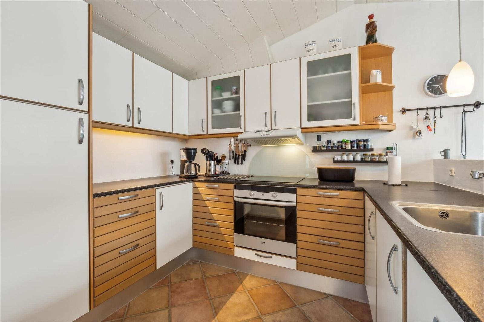 Kitchen with white cabinets, wood fronts, and stainless steel sink.