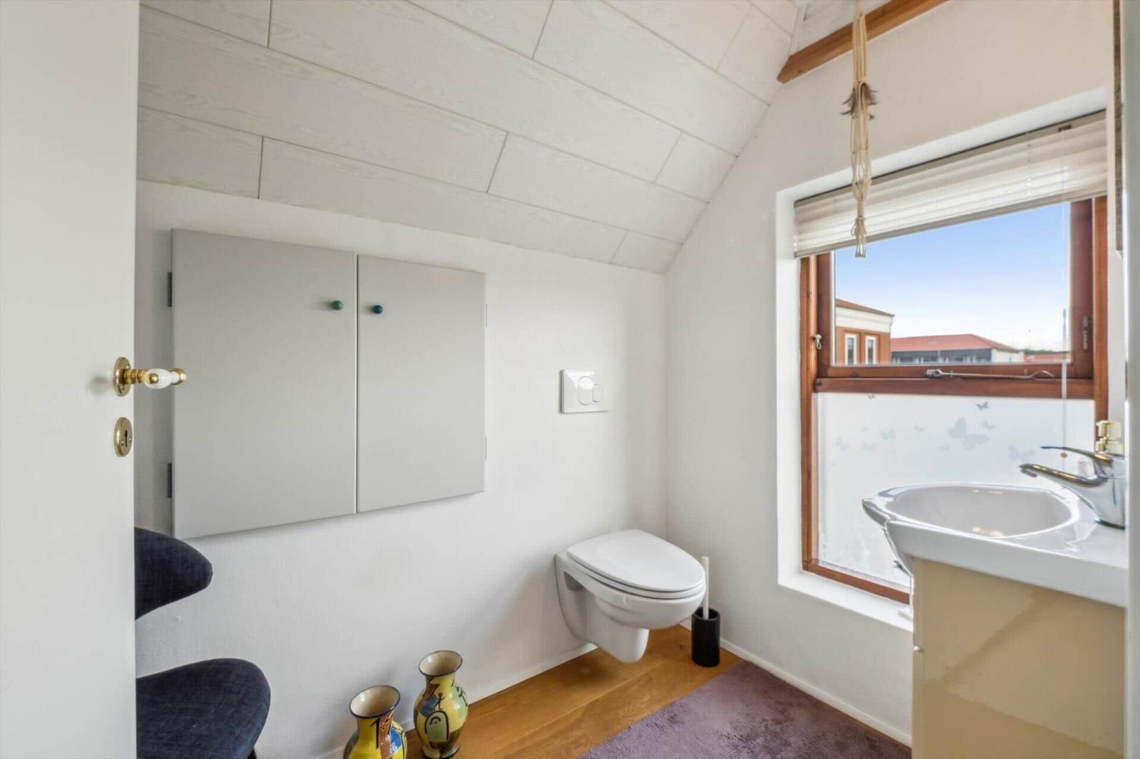 Bathroom with toilet, sink, and window with view.