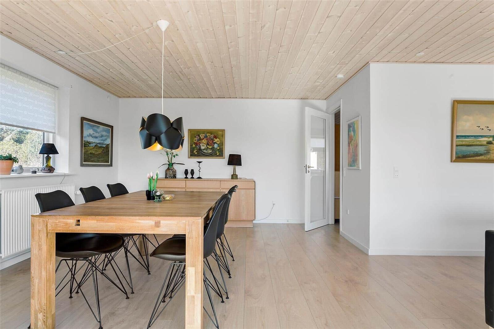 Esszimmer mit Holztisch, schwarzen Stühlen und Deckenlampe.