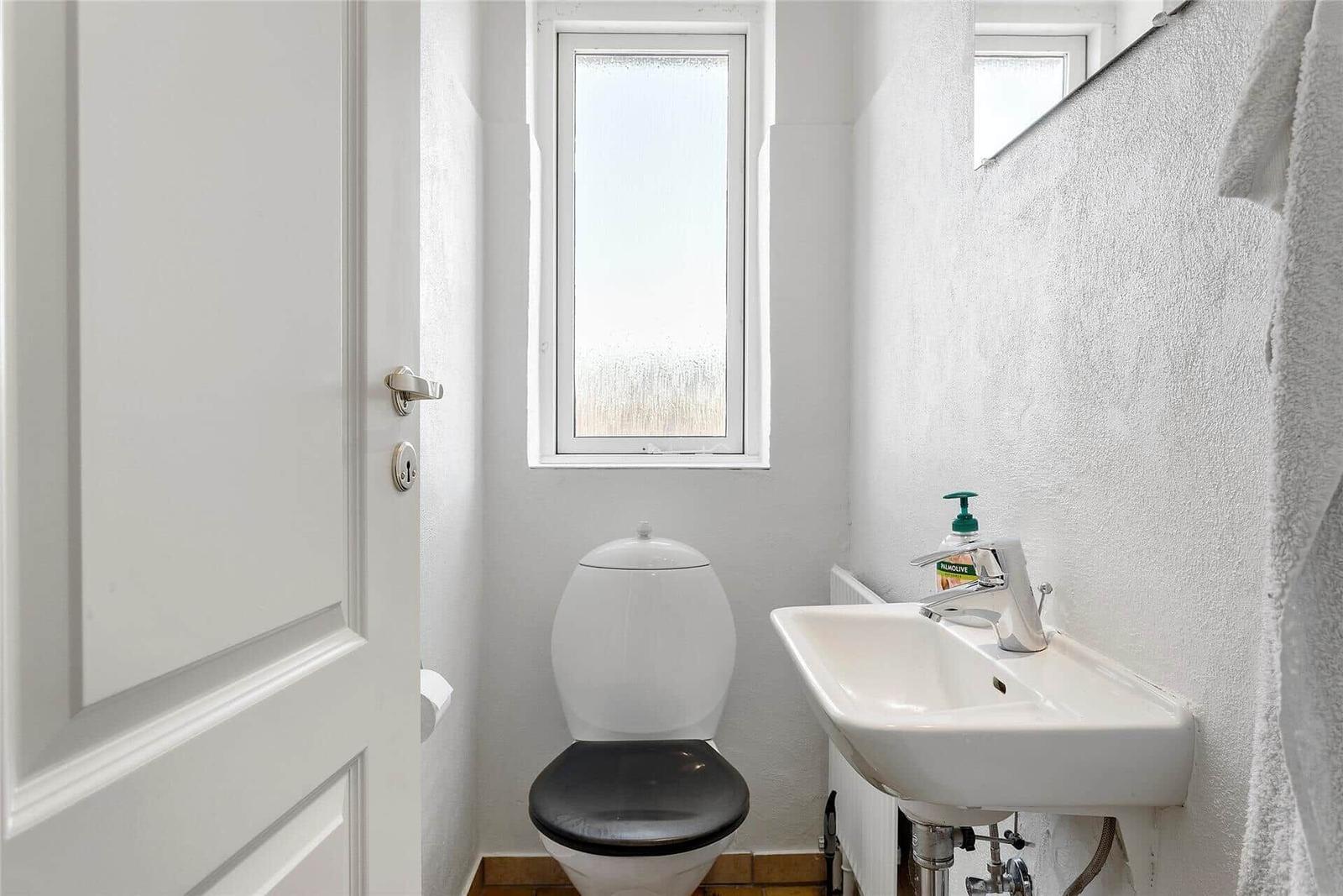 Badezimmer mit Toilette, Waschbecken und Fenster.