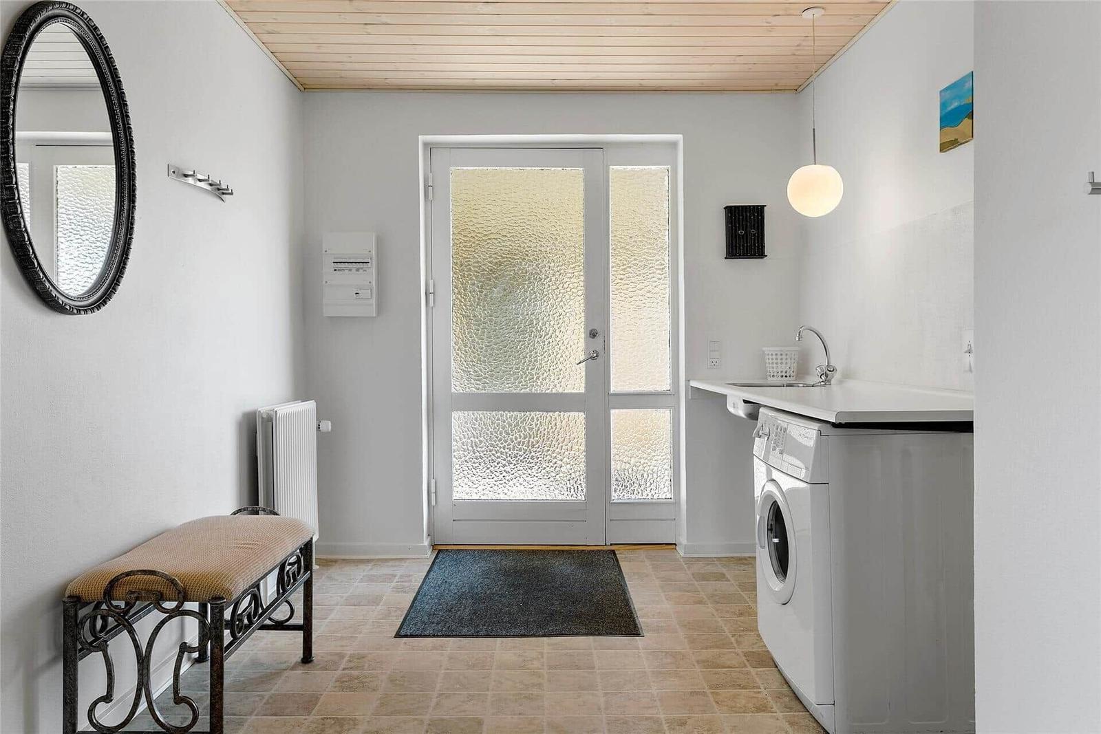 Eingangsbereich mit Waschmaschine, Spüle und Holzdecke.