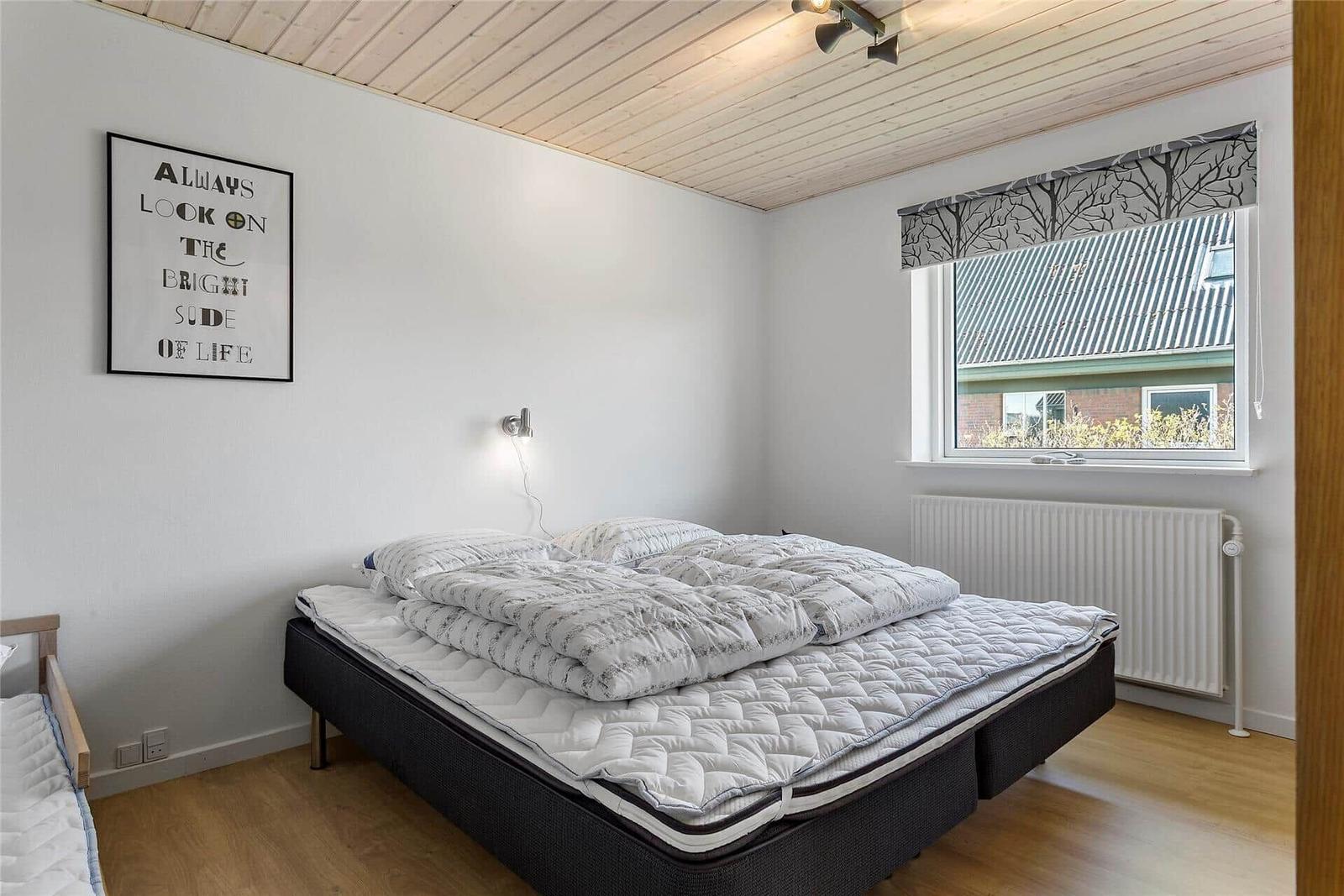 Schlafzimmer mit Bett, Fenster und Wandbild.