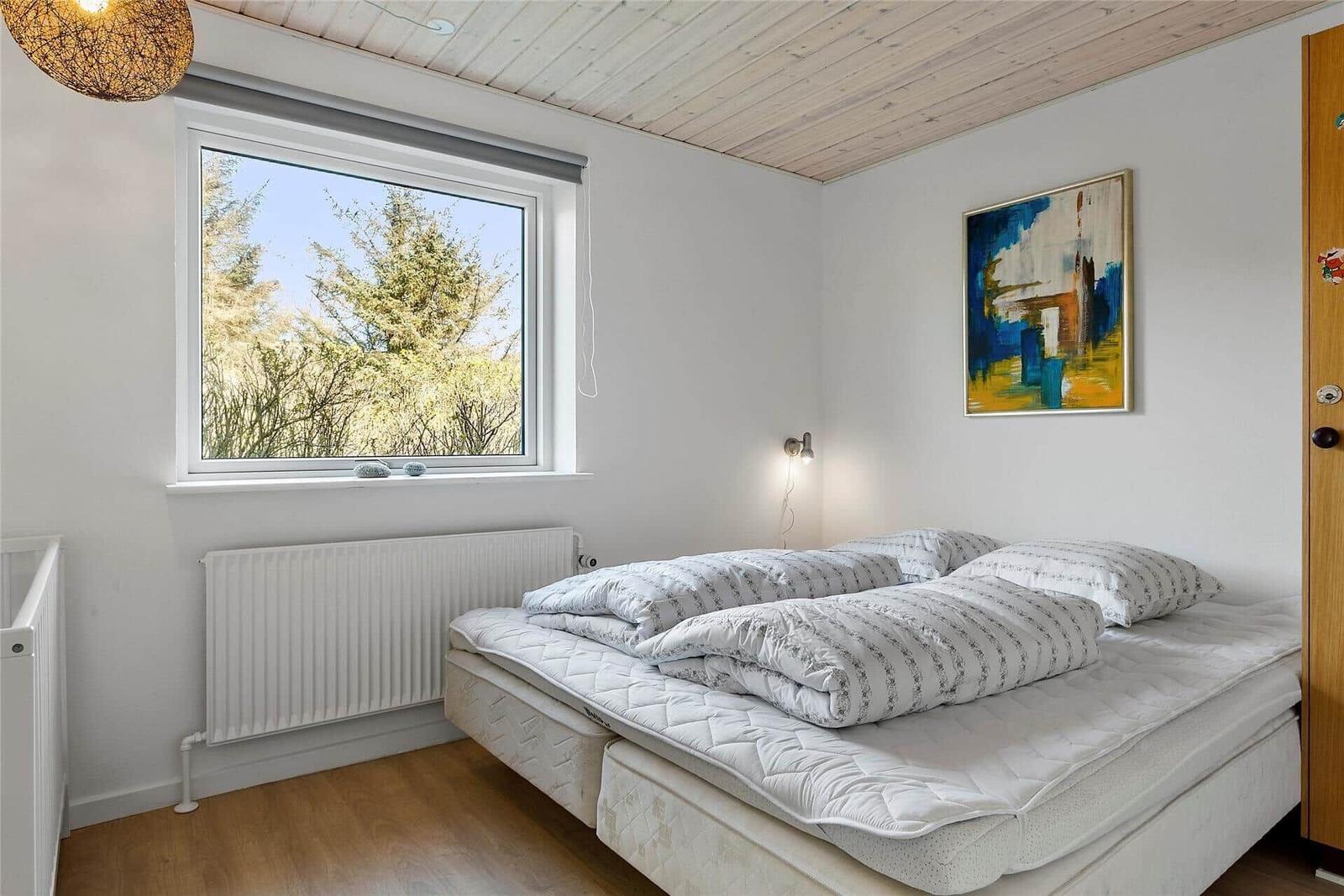 Schlafzimmer mit Doppelbett, Fenster und Gemälde an der Wand.