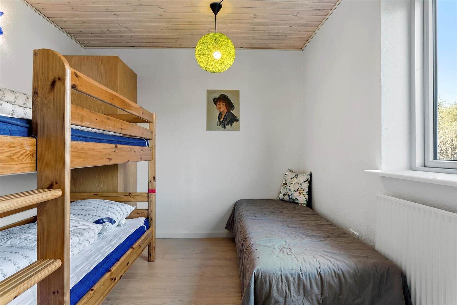 Zimmer mit Doppelstockbett und Einzelbett, Holzdecke, Fenster und Wandbild.