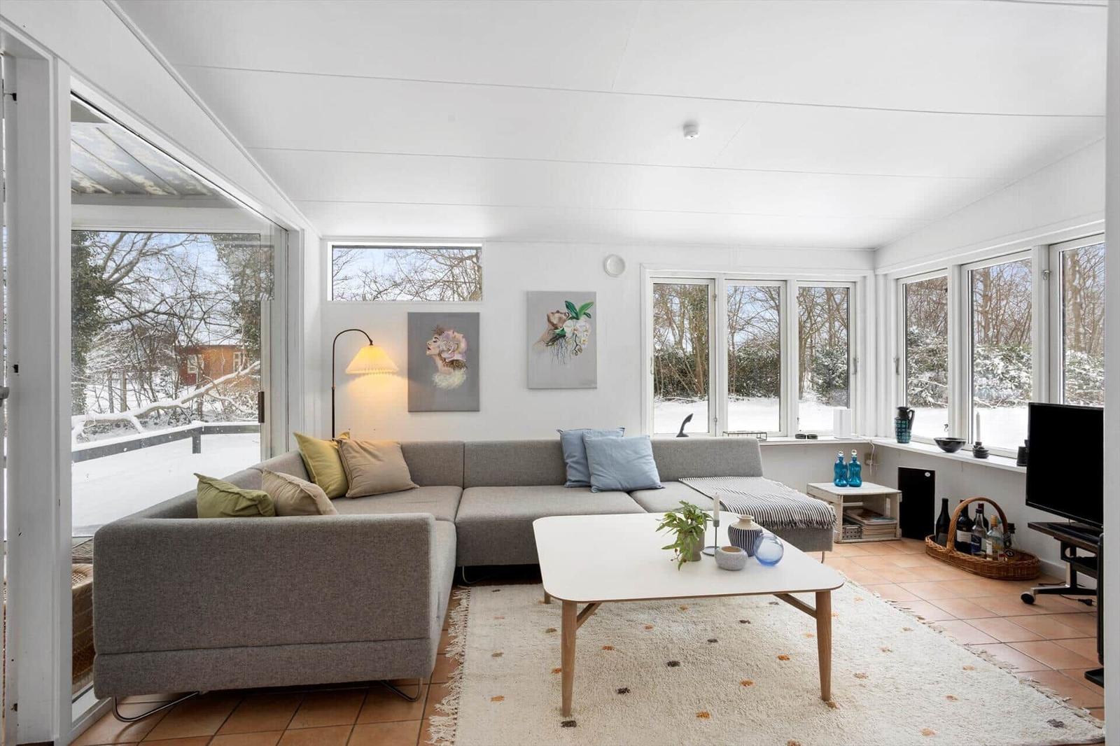 Living room with sofa, table, and windows to snow