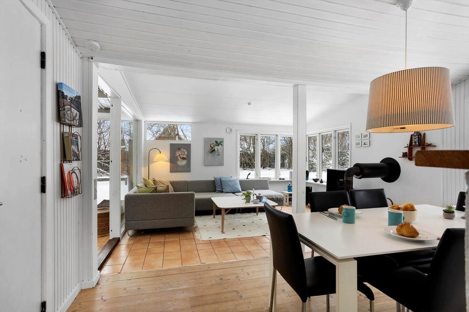 Living and dining area with sofa, table and chairs. Windows show snow.