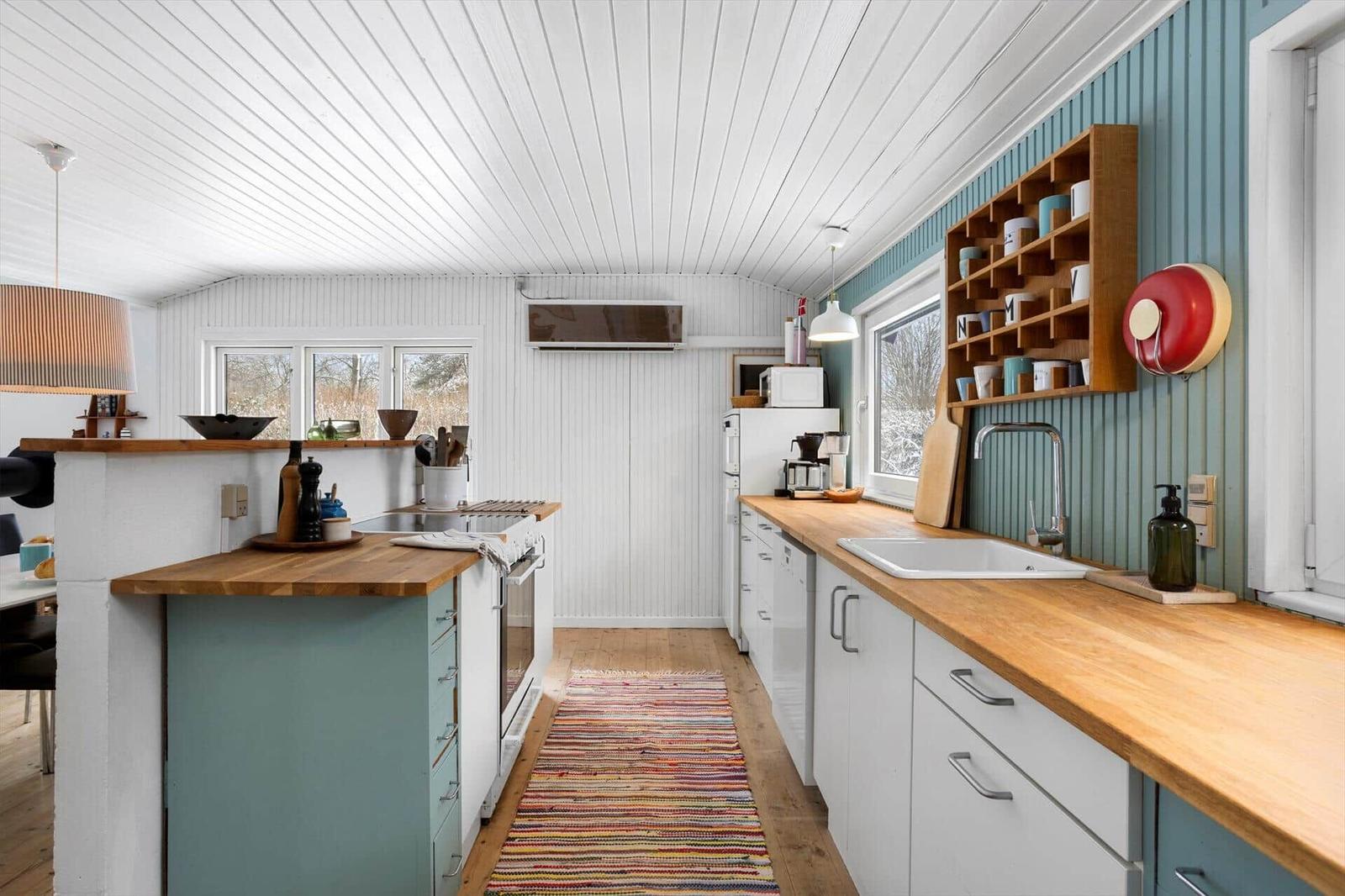 Kitchen with wooden surfaces, blue cabinets, and windows overlooking the garden.