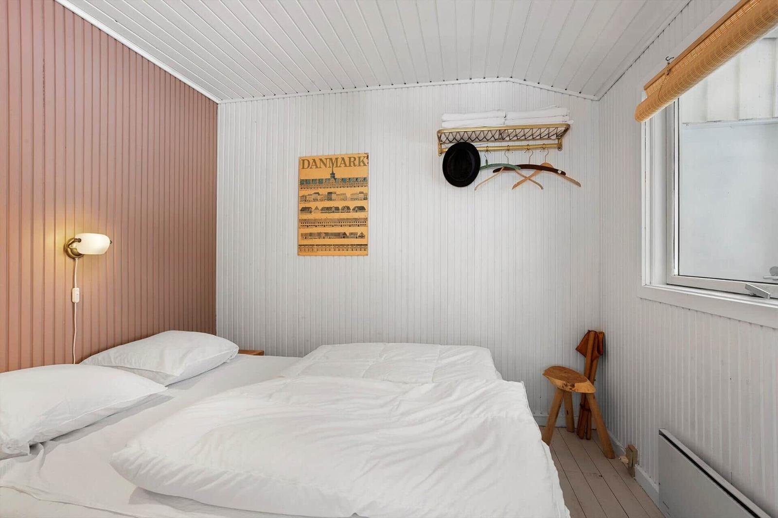 Bedroom with bed, wall poster, and coat rack on the wall.