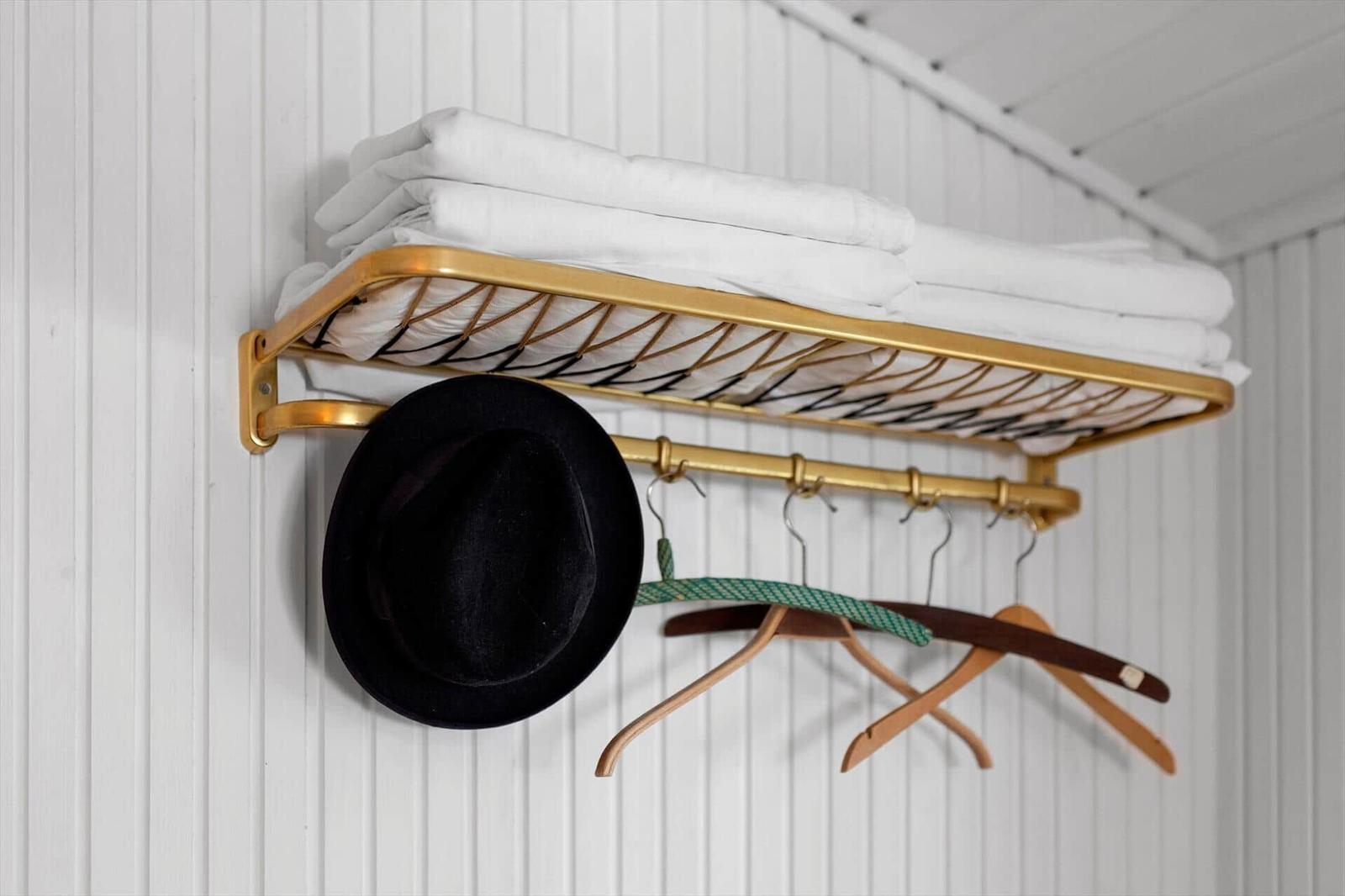 Wall rack with white towels, hat, and coat hangers.