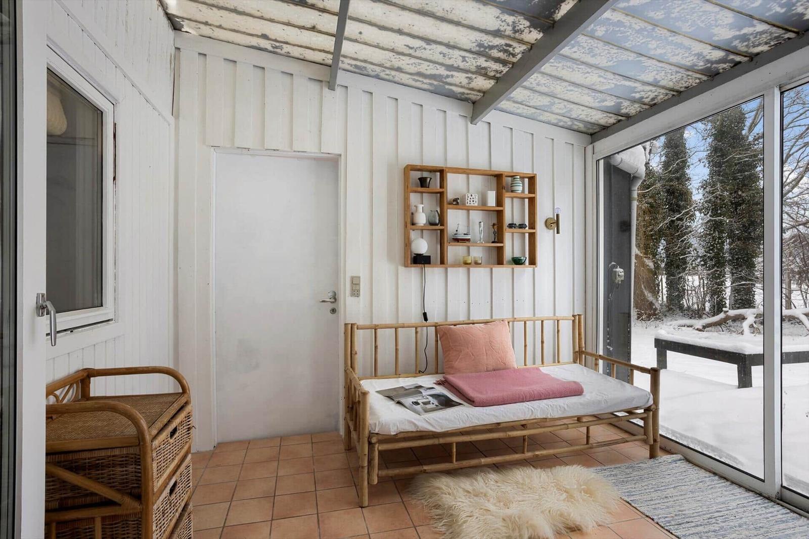 Room with bamboo bed, wall shelf, and terrace with snowy outdoor area.