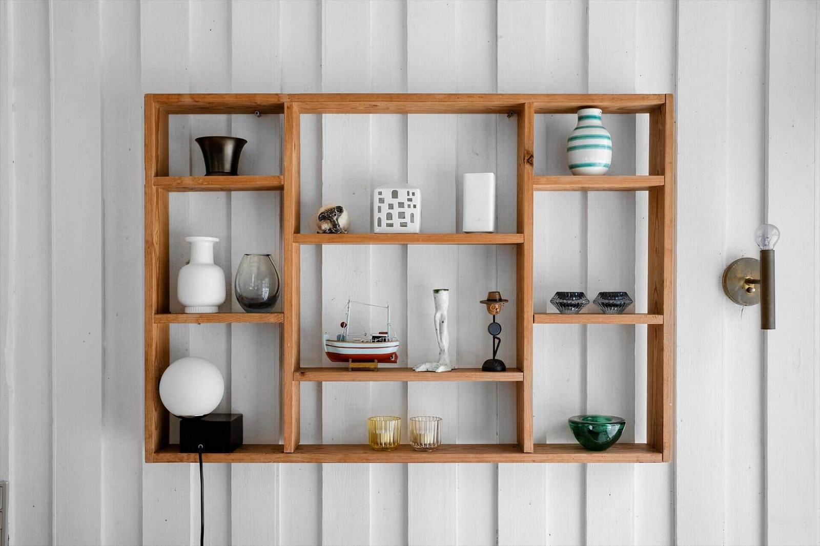 Wooden shelf on white wall with vases, ship model, and decor items.