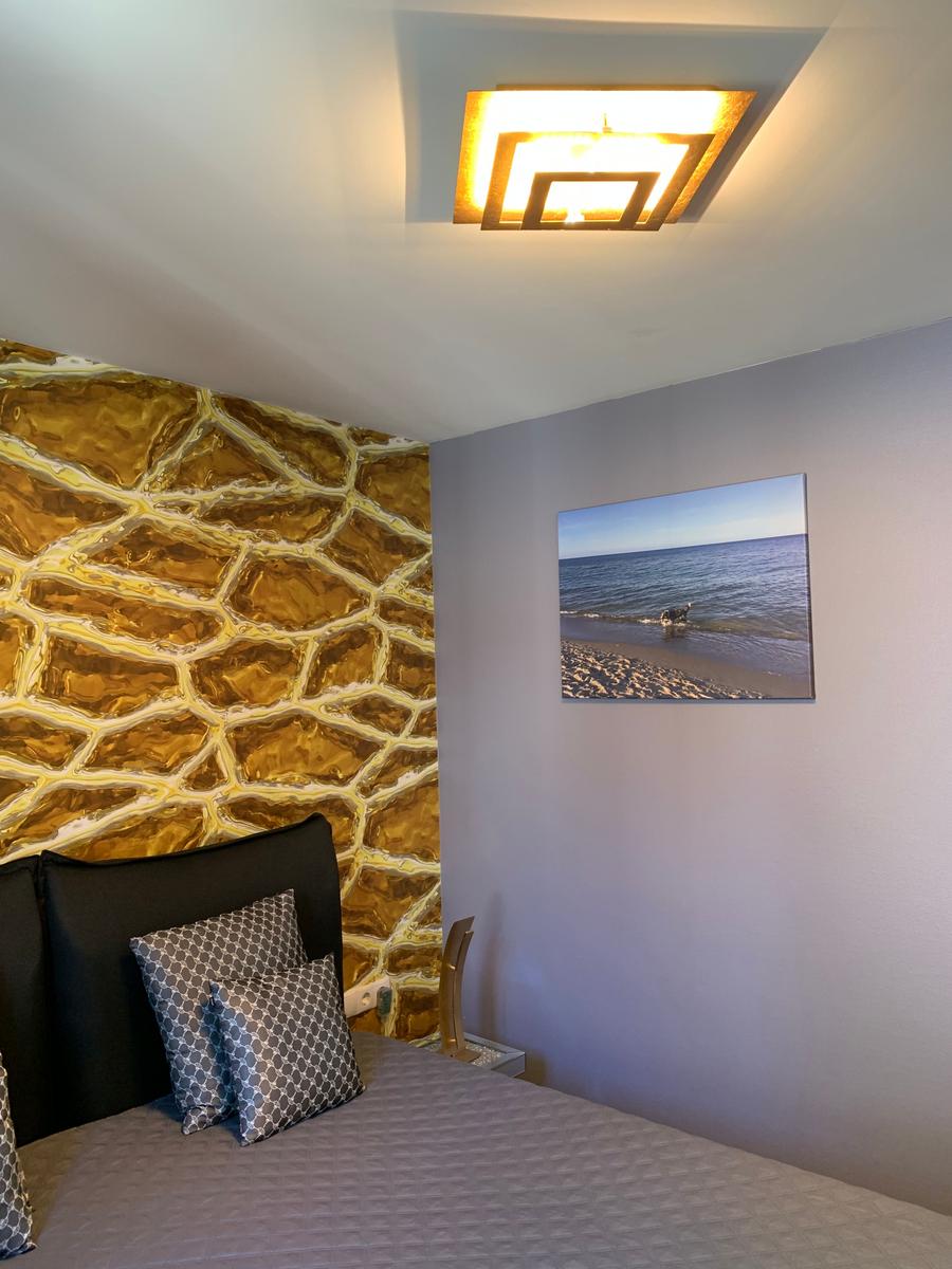 Schlafzimmer mit goldfarbener Wand und Strandbild an der Wand.