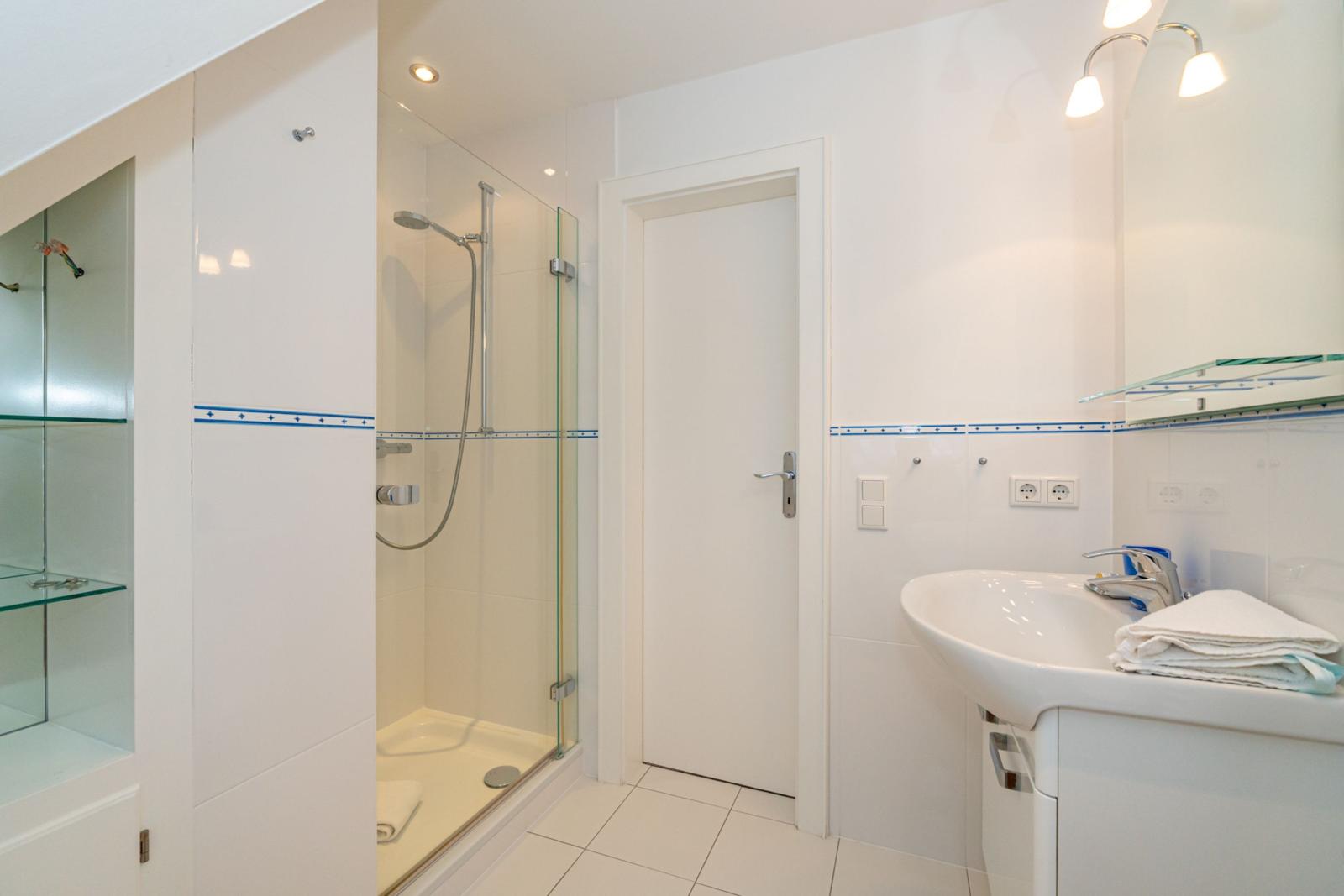 Badezimmer mit Dusche, Waschbecken und Spiegel