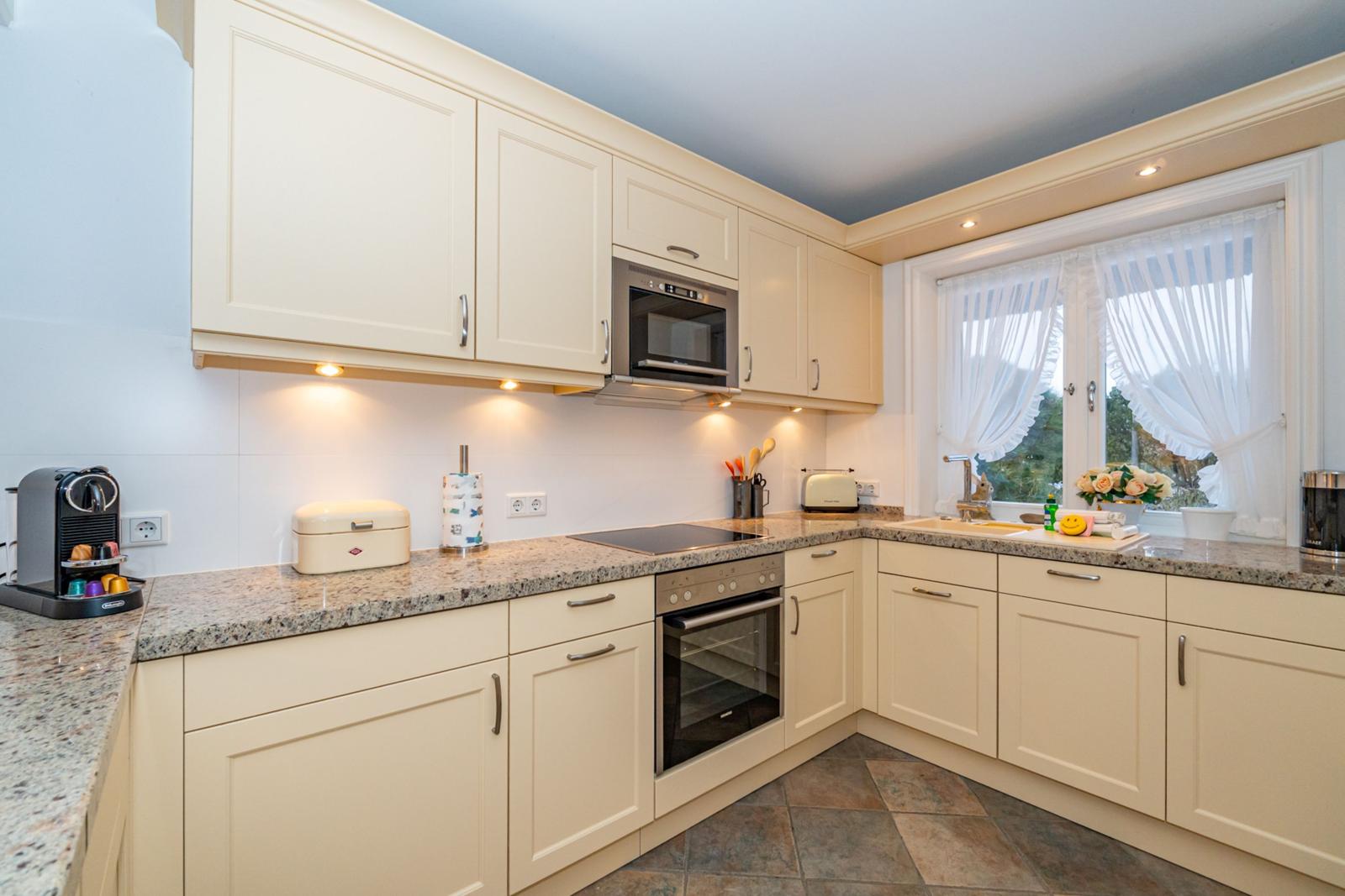 Küche mit cremefarbenen Schränken, Granit-Arbeitsplatte und integriertem Ofen.